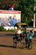 Laos: A pedicab or samlo in front of a revolutionary Socialist realist-style political poster on the streets of Vientiane